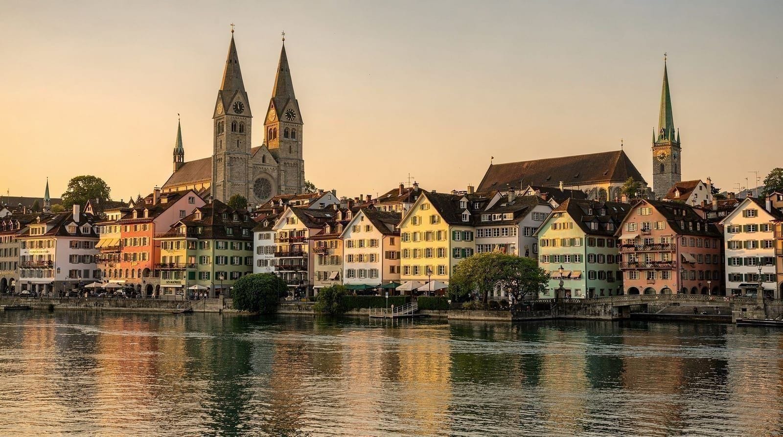 Il centro storico di Zurigo e il fiume Limmat al tramonto, con le Alpi visibili all'orizzonte.